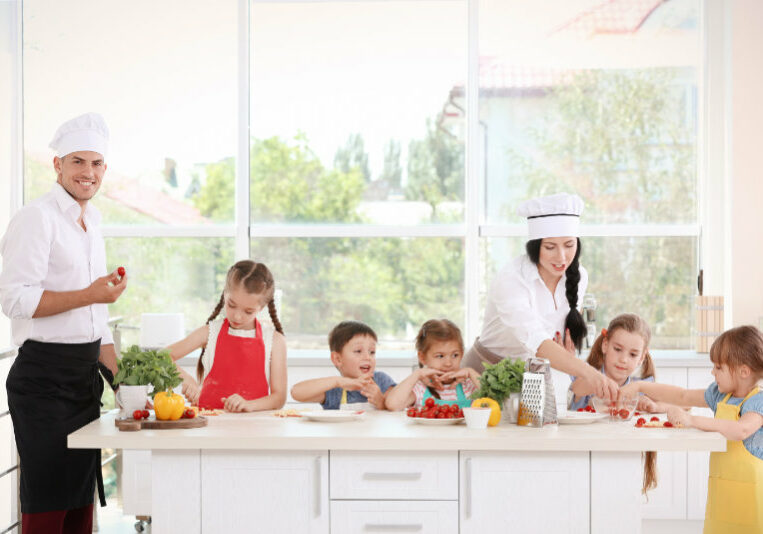 Two chefs and group of children during cooking classes