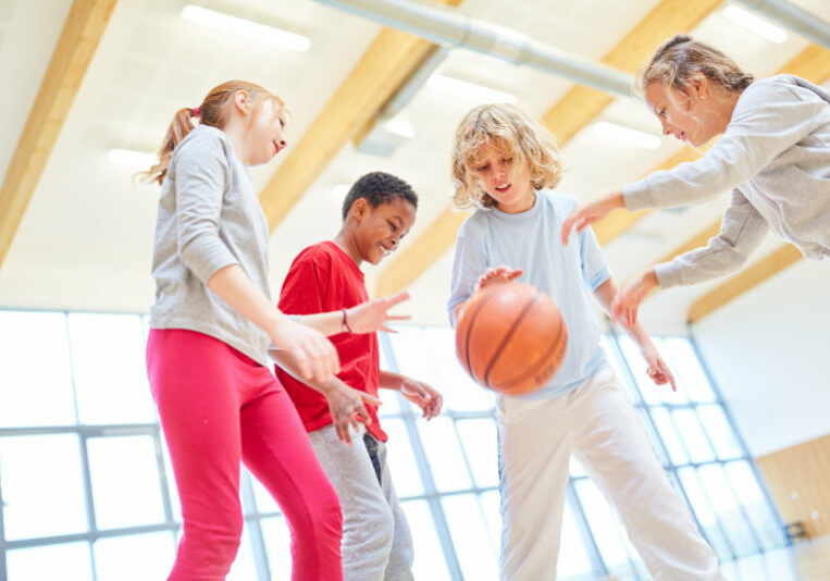 Gruppe Kinder als Basketball Team in der Turnhalle im Sportunterricht